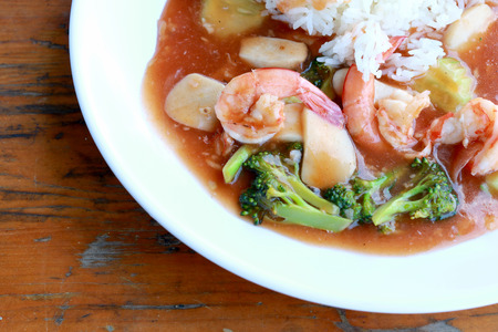 stir fried shrimp and Broccoli in thai red curry paste sauce with rice, Curry fried shrimps and cooked rice in white dish closeup on wooden table. Thai style food.の写真素材