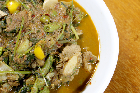 Northern Thai spicy curry with pork and mixed vegetables and Thai herbs with a Northern Spices in white blow on wooden table, Kaeng khae in Thai word, Northern style Curry,Thai northern style food.の写真素材