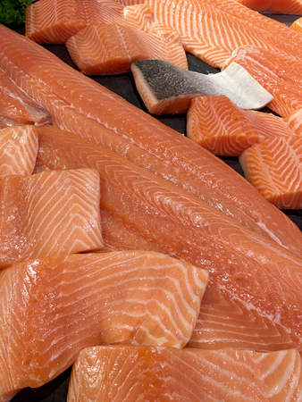 Sliced raw salmon or fresh salmon. Salmon fillets for sale at market displayed with a patchwork effect. Many fresh salmon fish meat slices in a black tray which are sale in the supermarket.の写真素材