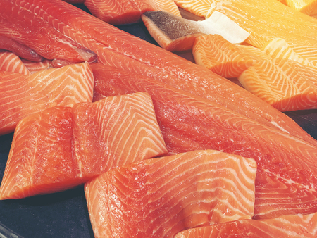 Sliced raw salmon or fresh salmon. Salmon fillets for sale at market displayed with a patchwork effect. Many fresh salmon fish meat slices in a black tray which are sale in the supermarket.の写真素材