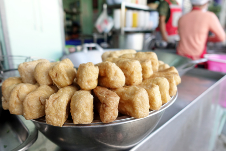 Crispy deep fried tofu after placed on the drying rack for the excess oil to drip off from street vendor at Thai street food vendor market, Vegetarian food, Thai food, snacks Thai style.の写真素材