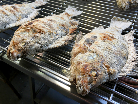 Cooking the Red tilapia grilled with salt and herb inside on the stove. Thai local food Salted grilled fish , One of a popular food in Thai street food marketの写真素材