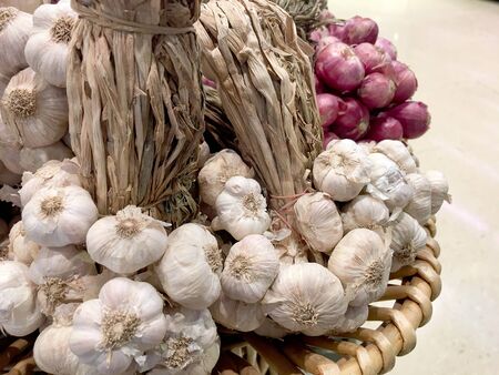 Red and white garlic bulbs, cloves and shallots on wooden background in local marketの写真素材