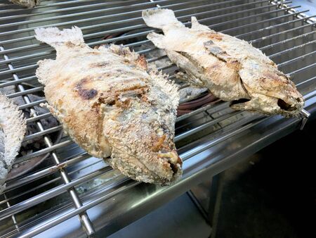 Cooking the Red tilapia grilled with salt and herb inside on the stove. Thai local food Salted grilled fish , One of a popular food in Thai street food marketの写真素材