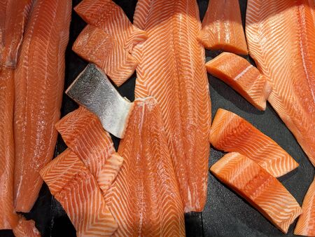 Sliced raw salmon or fresh salmon. Salmon fillets for sale at market displayed with a patchwork effect. Many fresh salmon fish meat slices in a black tray which are sale in the supermarket.の写真素材