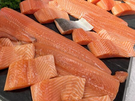 Sliced raw salmon or fresh salmon. Salmon fillets for sale at market displayed with a patchwork effect. Many fresh salmon fish meat slices in a black tray which are sale in the supermarket.の写真素材