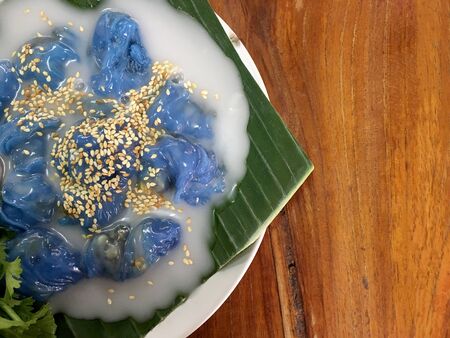 Steamed Tapioca Balls filled with Pork Recipe and Steamed rice skin dumplings with green banana leaf lettuce with milk on wooden table. Thai dessert style food. Top view & flat layの写真素材