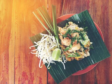 Pad Thai. Thai style fried noodles with shrimps prawns and vegetables on banana leaf on wooden table. Traditional Thai food menu for restaurant. Asian food.Top view & flat layの写真素材