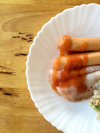 Homemade bavarian Sausages and Han in white paper dish for Breakfast in the morning on wooden table.の写真素材