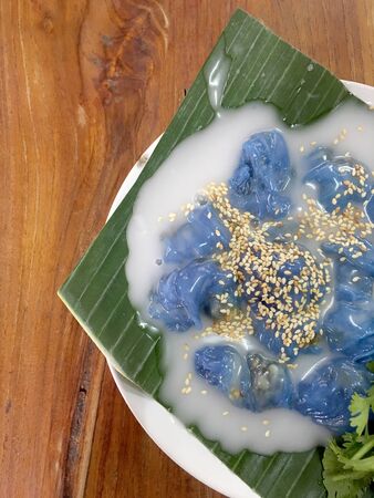 Steamed Tapioca Balls filled with Pork Recipe and Steamed rice skin dumplings with green banana leaf lettuce with milk on wooden table. Thai dessert style food. Top view & flat layの写真素材