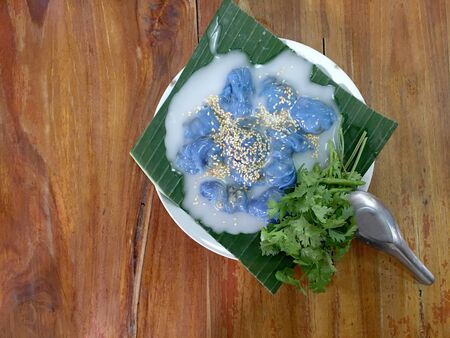 Steamed Tapioca Balls filled with Pork Recipe and Steamed rice skin dumplings with green banana leaf lettuce with milk on wooden table. Thai dessert style food. Top view & flat layの写真素材