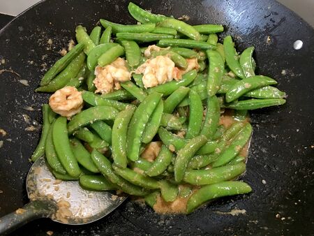 Vegetables Stir-Fry Recipe of pea with prawns or shrimps in black iron pan at the kitchen. Cooking concept.の写真素材