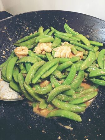 Vegetables Stir-Fry Recipe of pea with prawns or shrimps in black iron pan at the kitchen. Cooking concept.の写真素材
