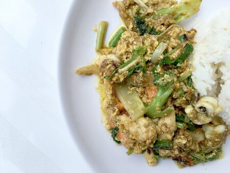 Stir fry mixed-seafood with with yellow curry powderin thai style with fried egg and rice in in white plate on white background.の写真素材