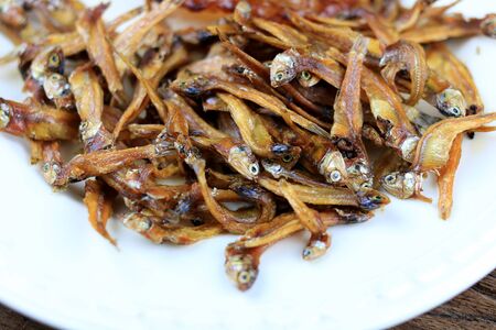 Fried giant catfish and pile of Deep fried small fishes (Minnow fish) Traditional Thai recipes in white dish on rustic wood background.  popular in Thailand, important export product of Thailand.の写真素材