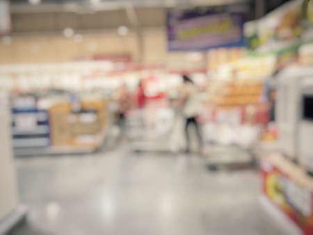 Blurred image of people shopping in supermarket. Cashier with long line of people waiting at checkout counter in fitness store at outlet shopping mall in Thailand.の写真素材