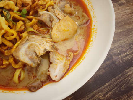 Khao Soi Kai, Thai spicy food in white blow on wooden table, Thai spicy soup. Thai Food. Northern Thai Style Curried Noodle Soup with Chickenの写真素材