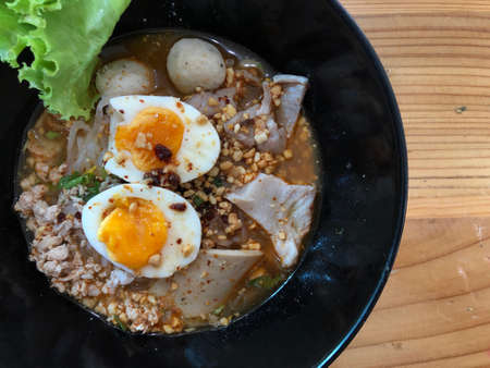 Spicy tom yam noodle soup with boiled egg, pork and bigの写真素材