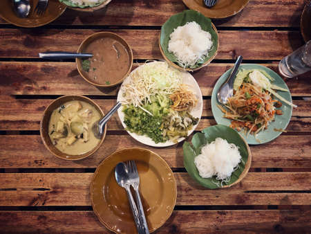 Rice noodles with curry sauce,  Green curry and fresh organic vegetable set on the table (eggplant, yardlong bean, banana blossom, pickled lettuce, bean sprouts, hairy basil) . Thai style food.の写真素材