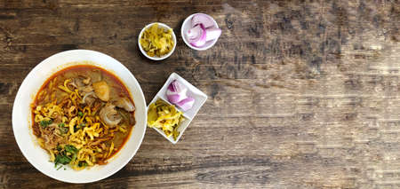 Khao Soi Kai, Thai spicy food in white blow on wooden table, Thai spicy soup. Thai Food. Northern Thai Style Curried Noodle Soup with Chickenの写真素材
