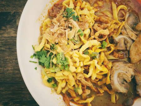 Khao Soi Kai, Thai spicy food in white blow on wooden table, Thai spicy soup. Thai Food. Northern Thai Style Curried Noodle Soup with Chickenの写真素材