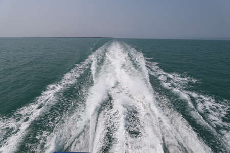 Ship wake on the ocean.aves from the back of a speed boat over the water's surface in sea. Waves behind a boat on a clear blue seaの写真素材