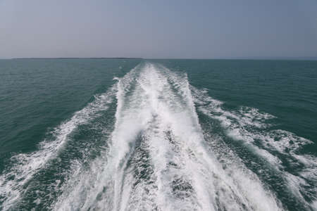 Ship wake on the ocean.aves from the back of a speed boat over the water's surface in sea. Waves behind a boat on a clear blue seaの写真素材