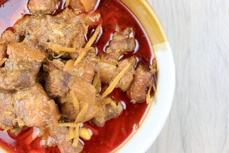 Thai Northern Style Hang Lay Curry in a bowl on wooden table.  A curry include pork, shallot, dried chillies, salt, garlic, spice masala mix, belly pork with Hang Lay Curry. Thai food.の写真素材