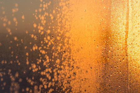 frozen water on glass in winter at sunsetの写真素材