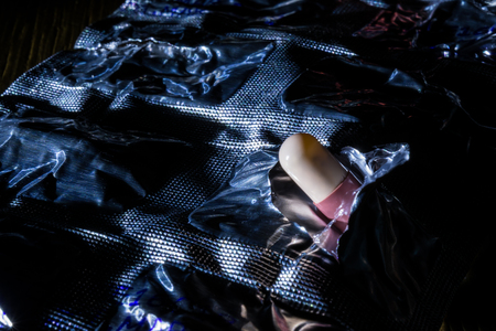 pill in torn packaging, blister, low key