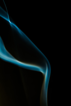 Smoke from burning incense sticks on dark backgroundの写真素材