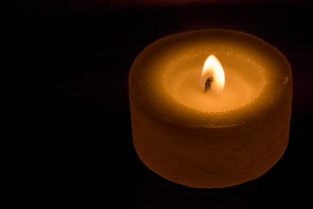 low candle burns at dusk, a candle fire on a black backgroundの写真素材