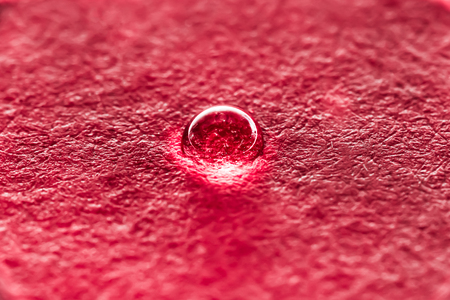 a drop of water on a red relief background, macro abstract backgroundの写真素材