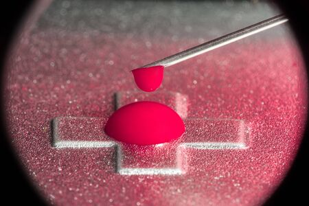 A red liquid drips from the syringe needle, abstract backgroundの写真素材