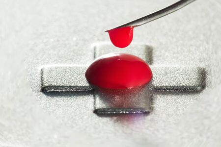 on the tip of a medical needle is a red blood drop, abstract backgroundの写真素材