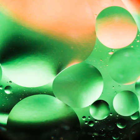 mixing water and oil, beautiful color abstract background based on green and orange circles and...