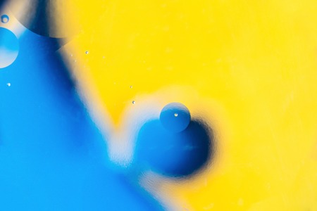 mixing water and oil, beautiful color abstract background based on yellow and blue circles and ovals, blurred macro abstractionの写真素材