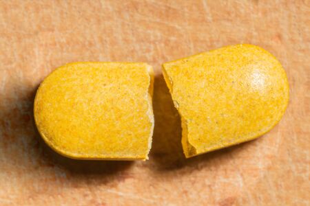 broken yellow pill in two pieces, macro abstraction backgroundの写真素材