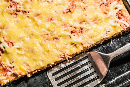 rectangular slice of pizza on the shoulder, cooked at home, dish on a black tray, food background close-upの写真素材
