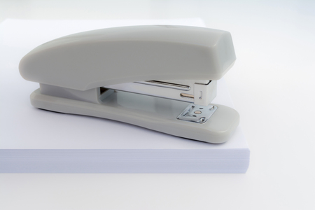 gray stapler is located on a pile of white paper, close-up abstract chancery backgroundの写真素材