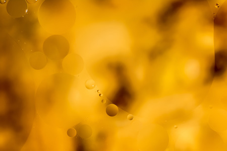 the interaction of water and oil, oil bubbles of various sizes on the water surface, orange abstract macro background with soft defocusingの写真素材