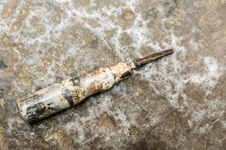 old screwdriver on rumpled shabby metal surface, close-up abstract backgroundの写真素材
