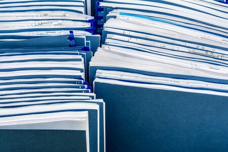Two row of blue folders with documents in paper box, close-up paperwork abstract background,...