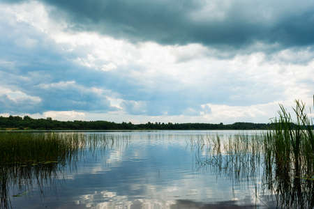 View from the coastline to the blue lake. Summer cloudy day. Nature landscape backgroundの写真素材