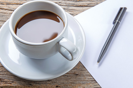 Cup of coffee, pen and paper on wooden tableの写真素材