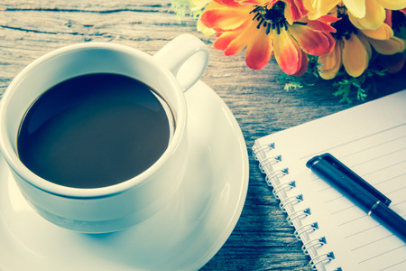 Cup of coffee, pen and notepad on wooden tableの写真素材