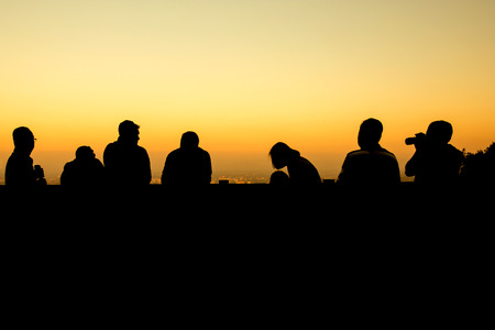 silhouette of group of friends standing in sunsetの写真素材