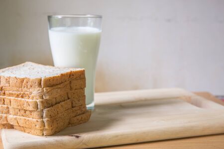 A Glass milk with bread slice on wood backgroundの写真素材