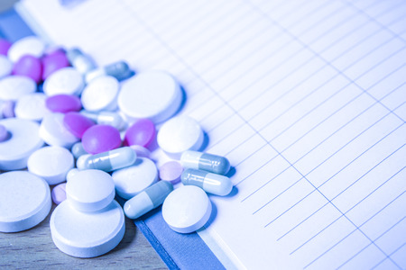 insulin syringe and colorful pill and capsules on wood background, in blue toneの写真素材