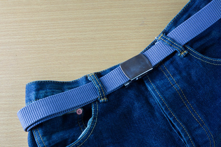 Blue jeans with belt on wooden backgroundの写真素材